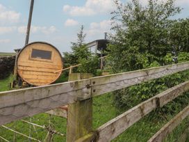 A shepherd's hut beside a fence and tree at The Herdsman Luxury Shepherds Hut in Barnoldswick