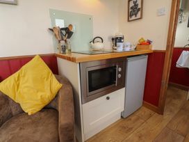 A kitchen area with a microwave, fridge, and utensils at The Herdsman Luxury Shepherds Hut in Barnoldswick