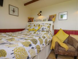 A bedroom with a bed and chair at The Herdsman Luxury Shepherds Hut in Barnoldswick