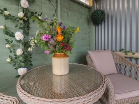 A flower vase on a wicker table in an outdoor seating area at The Herdsman Luxury Shepherds Hut Barnoldswick