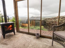 A conservatory with a wood stove and chair at The Herdsman Luxury Shepherds Hut Barnoldswick
