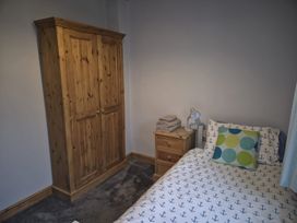 A bedroom with a bed and wardrobe at Ty Gwenyn in Rhydwyn