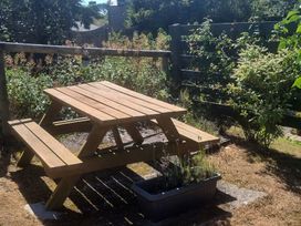 A picnic table with benches surrounded by plants at Ty Gwenyn in Rhydwyn
