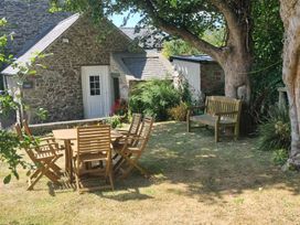 A garden with a table and chairs beside a house at Ty Gwenyn in Rhydwyn