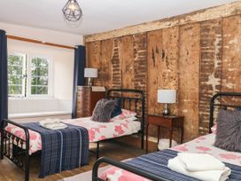 A bedroom with two beds and a wooden wall at The Abbey Grange near Charmouth