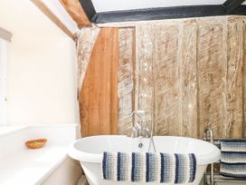 A bathroom with a bathtub and wooden walls at The Abbey Grange near Charmouth