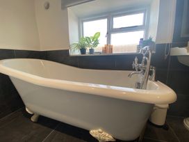 A bathroom with a bathtub and window at The Hollies Thurstonfield near Carlisle