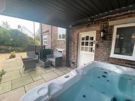 An outdoor patio with a hot tub and seating area at The Hollies in Thurstonfield near Carlisle