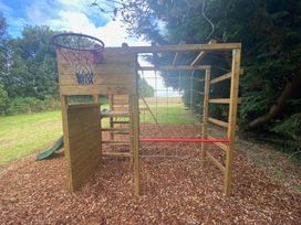 A climbing frame with a basketball hoop and slide in a garden at The Hollies in Thurstonfield near Carlisle