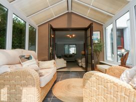 A conservatory with sofas and plants at Fairfield in Llanbedrog