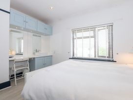 A bedroom with a bed, dresser, and windows at Fairfield in Llanbedrog