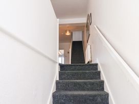 A carpeted staircase with white walls and handrails leading to a hallway with a ceiling light and a framed picture on the wall at Banks View Filey