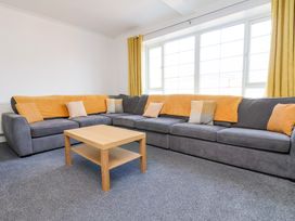 A living room with a gray sectional sofa with yellow pillows and throws and a wooden coffee table at Banks View Filey in Filey