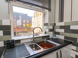 A kitchen sink with a drying rack dish soap and yellow flowers on the window sill at Banks View Filey