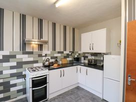 A kitchen with white cabinets a stove a refrigerator a microwave a toaster and tiled walls at Banks View Filey
