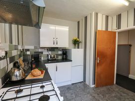 A kitchen with a stove, countertop appliances, a loaf of bread and vegetables on a cutting board at Banks View Filey in Filey