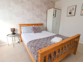 A bedroom with a wooden bed frame a side table with a lamp a wardrobe and framed pictures on the wall at Banks View Filey in Filey