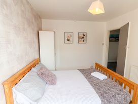 A bedroom with a wooden bed white and gray bedding a white wardrobe and two framed pictures on the wall at Banks View Filey