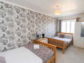 A bedroom with two wooden beds a bedside table with lamp and mirror a wardrobe and window with curtains at Banks View Filey in Filey