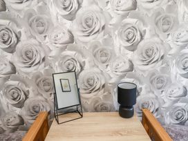 A table with a mirror and lamp against a wall with floral wallpaper at Banks View Filey