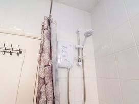 A bathroom shower area with a shower curtain rod shower head and an electric shower unit at Banks View Filey