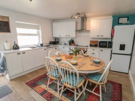 A kitchen with white cabinets and a round table at Bluebell Cottage in Flamborough