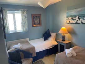 A bedroom with two beds and a lamp on a nightstand at 11 Penygroes in Llanddeusant