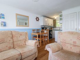 A sitting area with two beige sofas and a dining area with a wooden table and four chairs next to a kitchen at 8 The Park in Kilkhampton