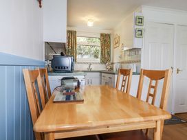 A kitchen dining area with a wooden table and chairs and kitchen appliances at 8 The Park in Kilkhampton