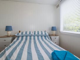 A bedroom with a bed with striped bedding and blue lamps on bedside tables at 8 The Park in Kilkhampton