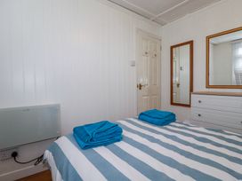 A bedroom with a striped bedspread two blue towels on the bed a white door a chest of drawers and two mirrors at 8 The Park in Kilkhampton