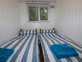 A small bedroom with two single beds with striped bedding and blue towels on each bed at 8 The Park in Kilkhampton