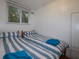 A bedroom with two single beds with blue and white striped bedding and blue towels by a window and a metal frame at 8 The Park in Kilkhampton