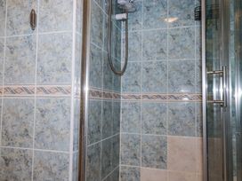 A tiled shower area with a showerhead and glass door at 8 The Park in Kilkhampton