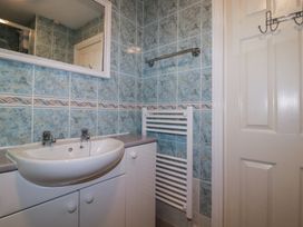A bathroom with a white sink and cabinet a wall mirror and a towel radiator at 8 The Park in Kilkhampton