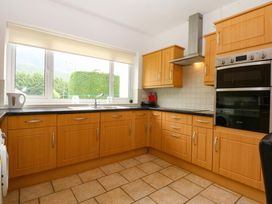 A kitchen with wooden cabinets and appliances at Y Berth in Caernarfon
