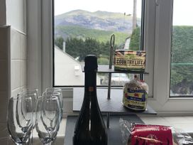 A kitchen with a champagne bottle and glasses near a window at Y Berth in Llanberis