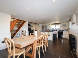 A kitchen and dining area with a wooden table and chairs a staircase and kitchen appliances at Penpethy Farm in Tintagel