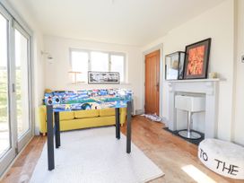 A game room with a foosball table yellow sofa and fireplace at Penpethy Farm in Tintagel
