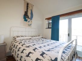 A bedroom with a bed with deer print bedding a wall hanging teal curtains and glass doors at Penpethy Farm in Tintagel
