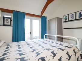 A bedroom with a bed covered in deer print bedding blue curtains a gray wardrobe and framed pictures on the wall at Penpethy Farm in Tintagel