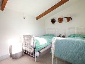 A bedroom with two single beds green bedding and stuffed animal heads mounted on the wall at Penpethy Farm in Tintagel