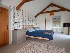 A bedroom with a wooden bed blue bedding bedside tables and a TV on a chest of drawers at Penpethy Farm in Tintagel