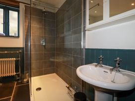 A bathroom with a walk-in shower, pedestal sink, radiator, and a small window at Penpethy Farm in Tintagel