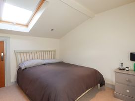 A bedroom with a bed near a skylight window and a nightstand with a lamp and phone at Penpethy Farm in Tintagel