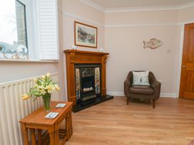 A living room with a fireplace and a chair at Maypole Cottage in Fylingthorpe