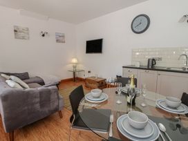 A living room with a dining area and kitchen unit at Swallows Retreat in Tenby