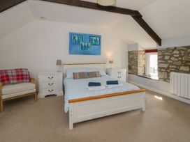 A bedroom with a bed and armchair at Swallows Retreat in Tenby