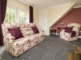A living room with floral patterned sofa and armchair with purple cushions and curtains at 2 Crosslands in Stockton-On-The-Forest