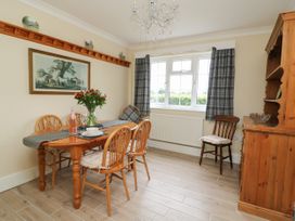 A dining room with a wooden table and chairs a chandelier and a window with plaid curtains at 2 Crosslands in Stockton-On-The-Forest
